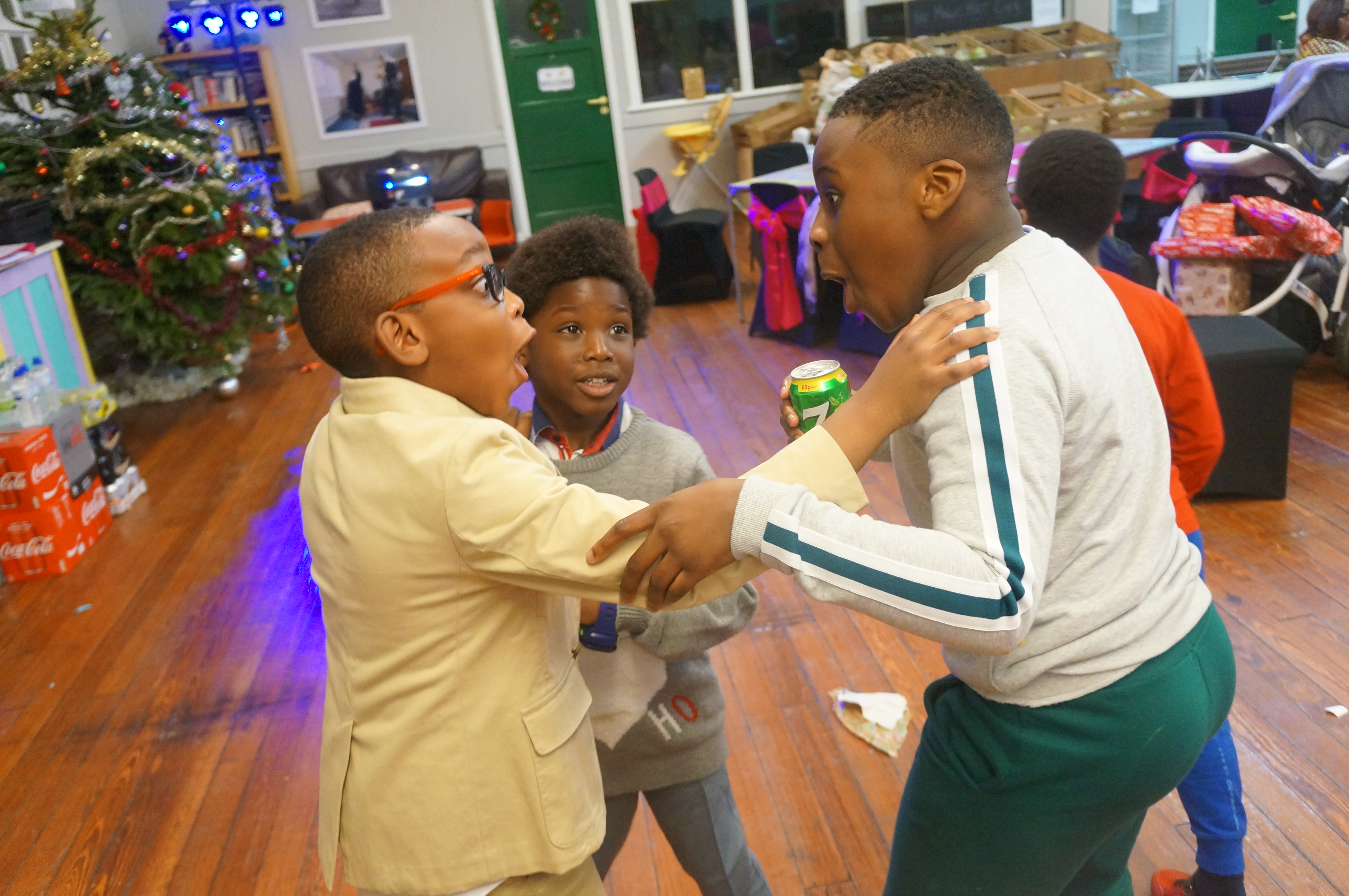 Three boys playing together near decorated Christmas tree