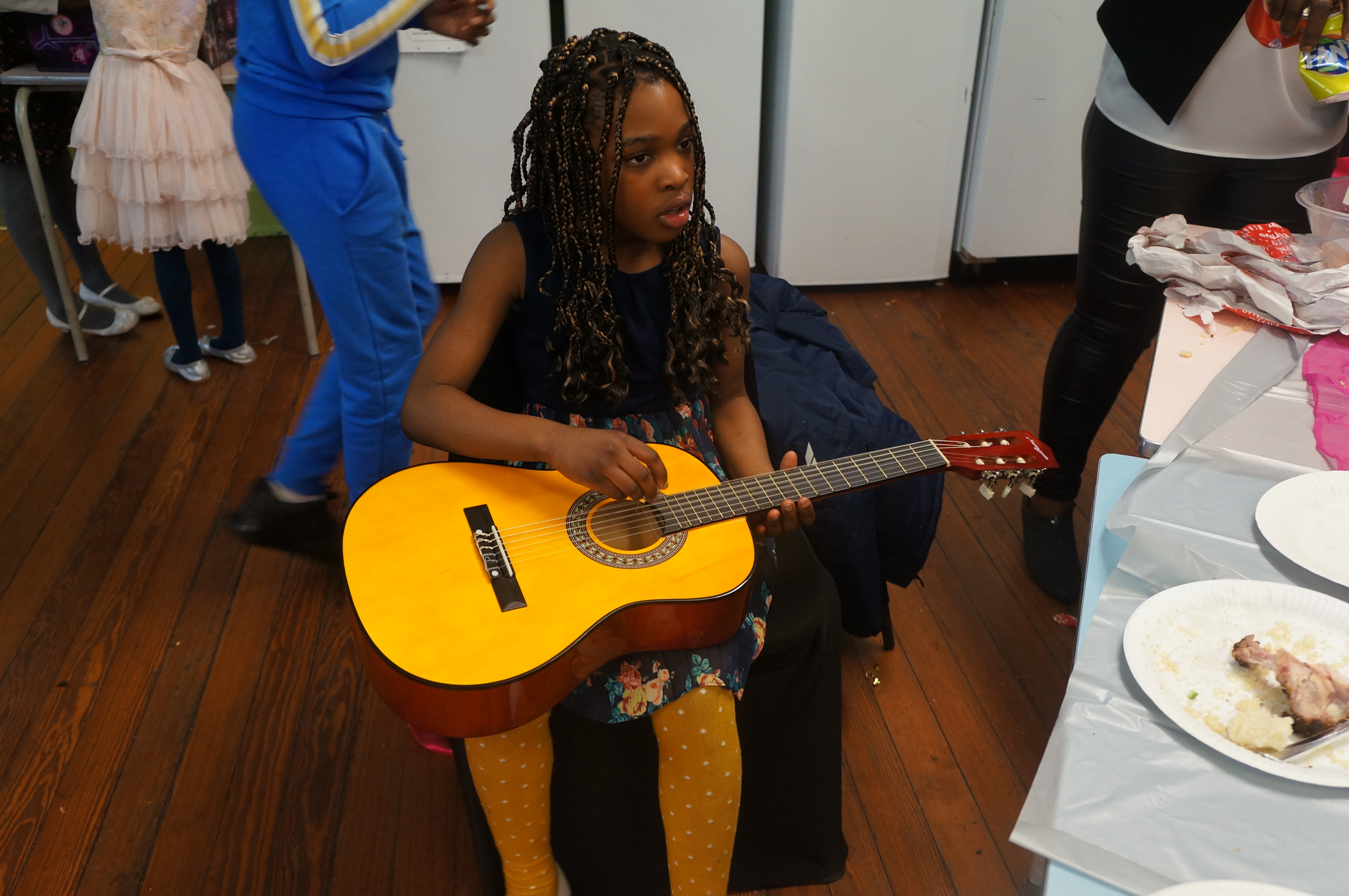 Young girl with braided hair playing yellow guitar at event