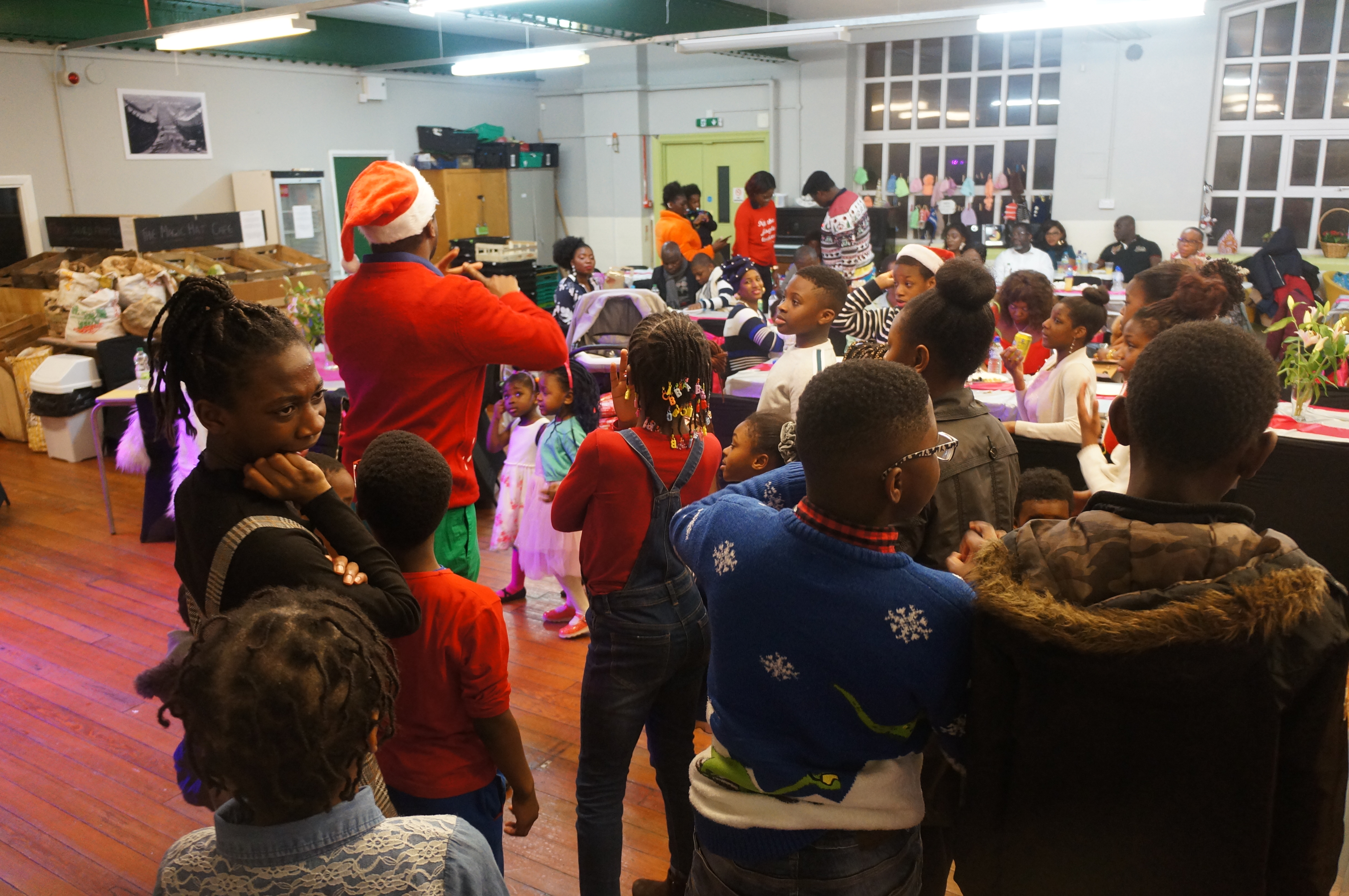 Volunteer in Santa hat engaging with children at community gathering